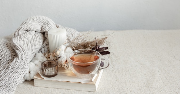 Stillleben im skandinavischen stil mit einer tasse tee, einem gestrickten element und einem buchkopierraum.