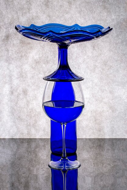 Stillleben mit blauer Flasche, Glas und blauer Vase auf grauem Hintergrund