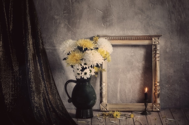 Stillleben mit Chrysanthemen und goldenem Holzrahmen auf alter Hintergrundwand