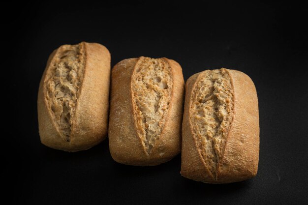 Foto stillleben mit drei brötchen, die zusammen auf einem schwarzen hintergrund platziert sind