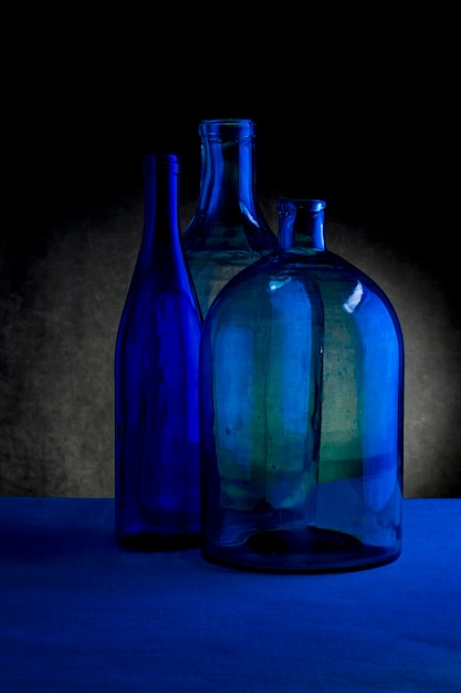 Stillleben mit drei Glasflaschen auf dunklem Hintergrund