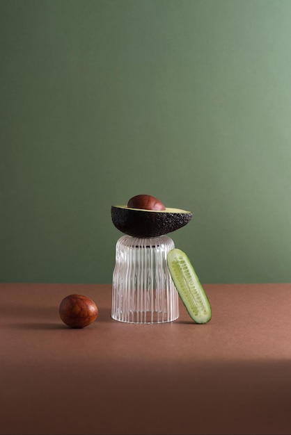 Stillleben mit einer Glas-Avocado und Gurke auf grünem Hintergrund Kreatives Konzept Prop-Styling und Bühnenbild