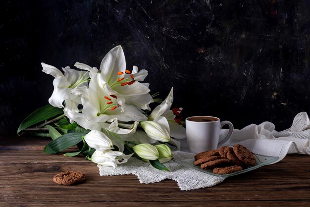 Foto stillleben mit einer tasse kaffeekekse und weißen lilien in nahaufnahme