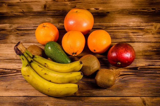 Stillleben mit exotischen Früchten Bananen Mango Orangen Avocado Grapefruit und Kiwis auf rustikalem Holztisch