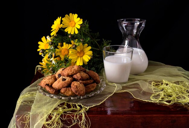 Stillleben mit gelber Gänseblümchenmilch und hausgemachten Keksen in der Nähe