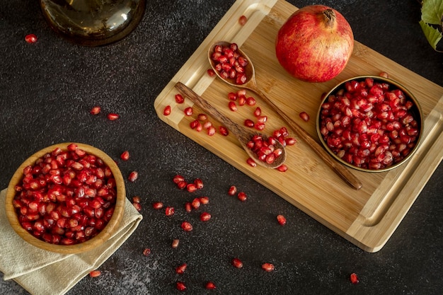 Stillleben mit Granatapfelkörnern aus roten Früchten auf Tellern und Löffeln