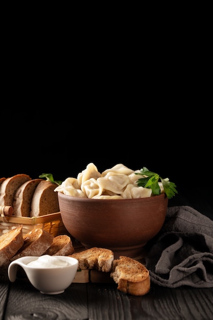 Foto stillleben mit heißen teigtaschen in einer tonschüssel und geröstetem roggenbrot