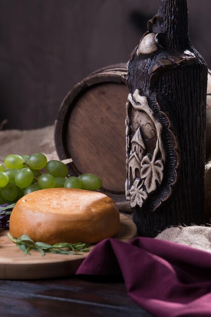 Stillleben mit Käse, Weinflasche und Trauben auf einem Hintergrund