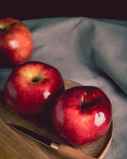 Stillleben mit Red Delicious Äpfeln und einem Messer auf einem Holzteller