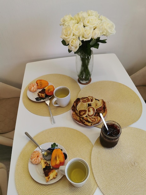 Stillleben mit Rosenstrauss und Frühstücksspeisen Festlich gedeckter Tisch