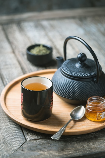 Stillleben mit schwarzer Teetasse mit Teekanne auf einem Tablett über Holztisch. Teestunde in gemütlicher Atmosphäre