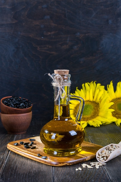 Stillleben mit Sonnenblumenöl in Glasflasche, Samen und Sonnenblume