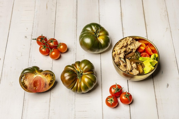 Stillleben mit süßer Marmelade aus Tomaten, Kirschtomaten und Salat in einer goldenen Schüssel auf einem weißen Tisch