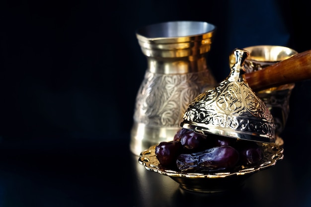 Stillleben mit traditionellem goldenem arabischem Luxuskaffeesatz mit jezva, Schale und Daten. Ramadan-Konzept.