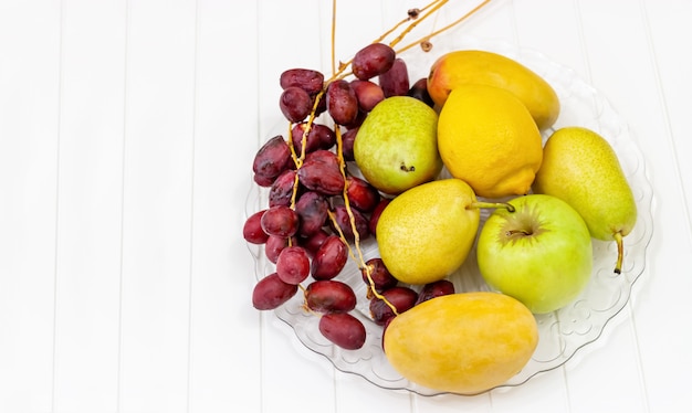 Stillleben Obst, Apfel, Birne, Mango, Zitrone und frische Datteln auf Glasplatte.