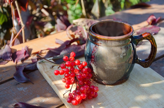 Foto stillleben-tonbe mit heißem tee-zweig aus viburnum zur dekoration