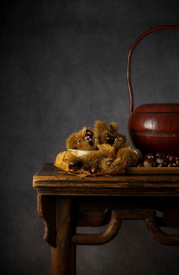 Foto stillleben von kastanien und kastanienfrüchten auf einem holztisch vor schwarzem hintergrund