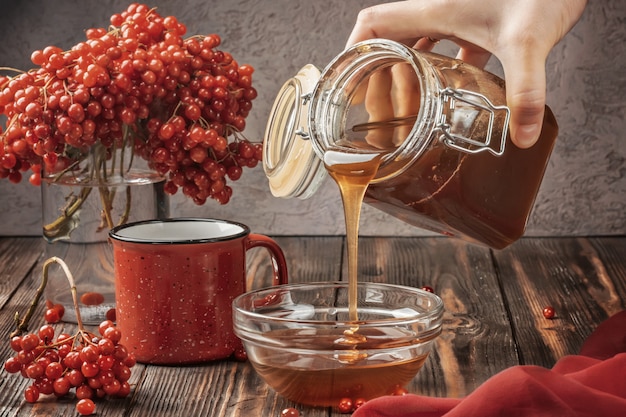 Stilllebenbeeren eines Viburnum in einem Glas und einem Becher heißem Tee und Honig