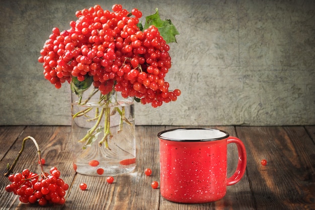 Foto stilllebenbeeren eines viburnum in einem glas und in einem becher heißem tee