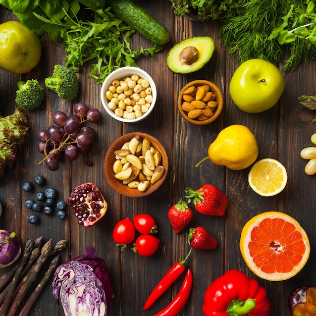 Stilllebenbild einer Auswahl an mehrfarbigem, köstlichem frischem Gemüse, Obst und Nüssen, flachgelegte Draufsicht. Gesundes Lebensstilkonzept