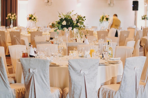 Stilvoll dekorierte Tische mit Rosensträußen Tellergläsern Besteck beim Hochzeitsempfang Luxus-Catering Weihnachts- und Neujahrsfest Feiern und Partykonzept