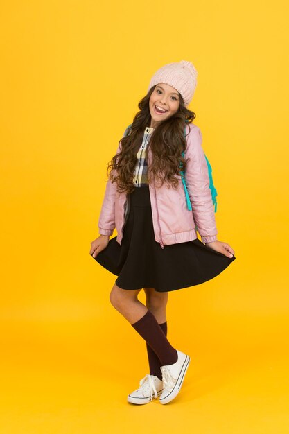 Stilvoll für zusätzliche saisonale Wärme. Stilvolles Mädchen zurück zur Schule. Kleines Kind im stilvollen Herbst trägt gelben Hintergrund. Verleihen Sie Ihrer Schulgarderobe einen stilvollen Look. Mode und Stil.