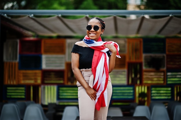 Stilvolle afrikanisch-amerikanische Frau mit Sonnenbrille posierte im Freien mit usa-Flagge