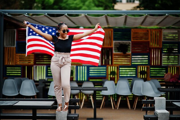 Stilvolle afrikanisch-amerikanische Frau mit Sonnenbrille posierte im Freien mit usa-Flagge