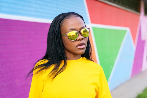 Stilvolle Afro-Frau in reflektierender Brille farbenfrohe städtische Kulisse