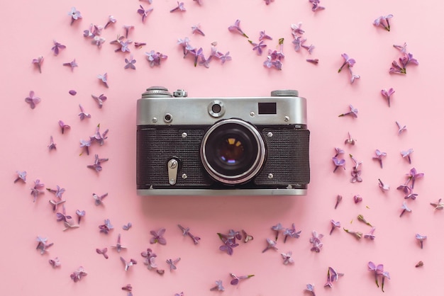Stilvolle alte Fotokamera auf rosa Hintergrund mit lila Blumen kreative Reise trendige Wohnung lag mit Platz für Text moderne Mode und Hipster-Bild Sommerurlaubskonzept
