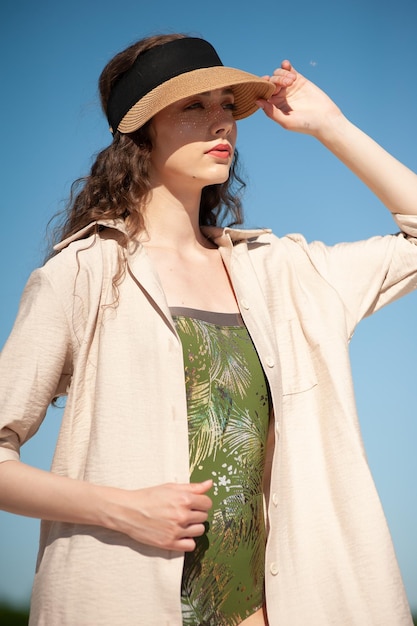 Stilvolle, attraktive, schlanke, lächelnde Frau am Strand im Sommerstil, Modetrend-Outfit, glücklich, Spaß zu haben