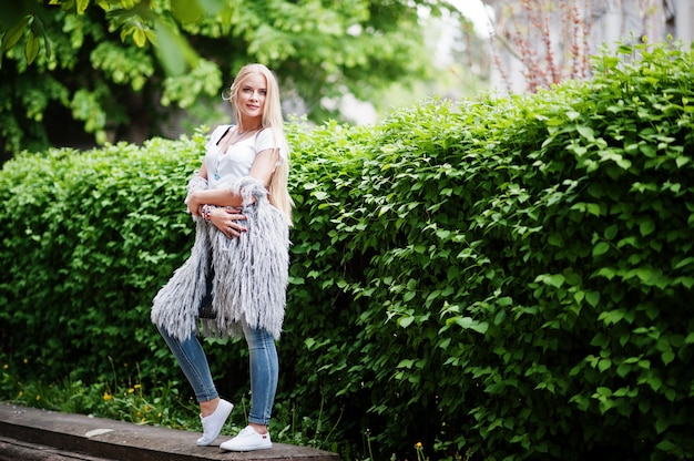 Stilvolle Blondine tragen an den Jeans und an Mädchen, die mit weißem Hemd ärmellos sind