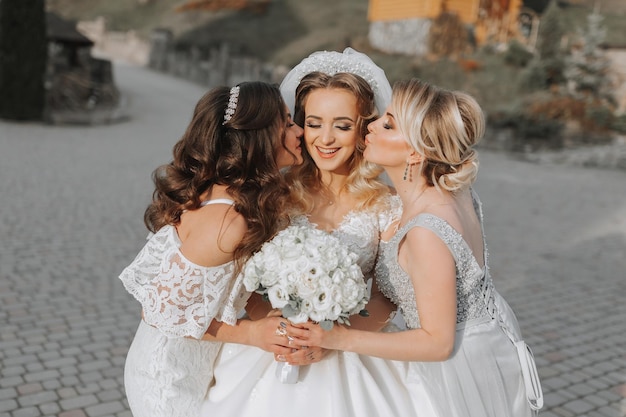 Stilvolle Brautjungfern haben Spaß mit der Braut in der Natur und posieren und küssen die Braut