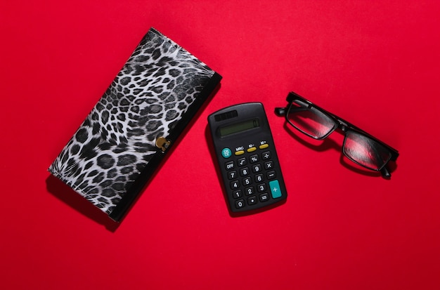 Stilvolle Brieftasche, Brille und Taschenrechner auf einem roten.