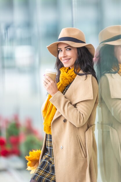 Stilvolle, elegante junge Brünette in einem Einkaufszentrum an einem kühlen Herbsttag.