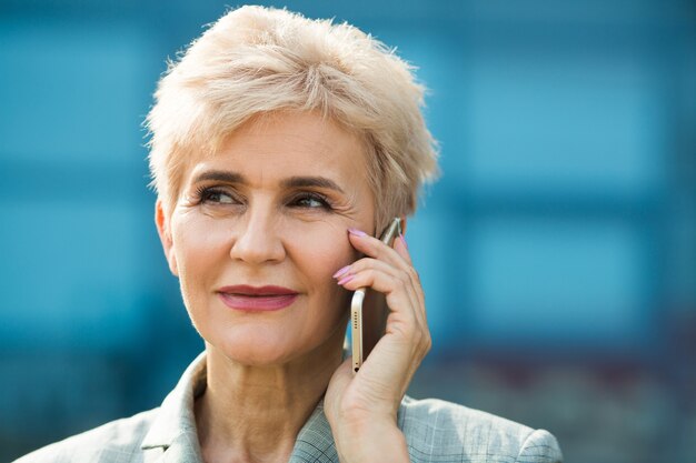 stilvolle erwachsene Frau im Anzug mit Handy