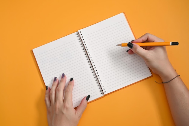 Stilvolle Frau, die Bleistift hält und auf leeres Notizbuch schreibt