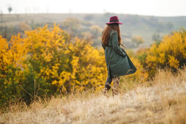 Stilvolle Frau, die Herbstwetter auf der Wiese genießt