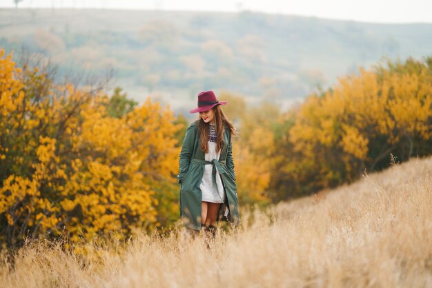 Stilvolle Frau, die Herbstwetter auf der Wiese genießt