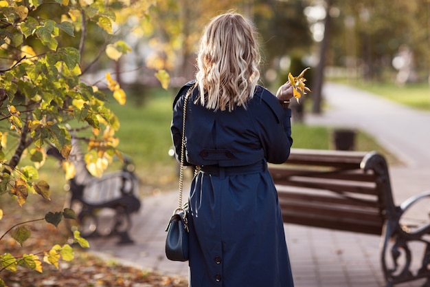 Stilvolle Frau geht in den Herbstpark.