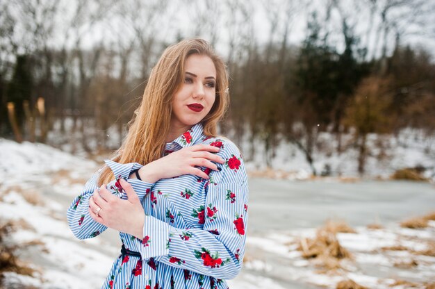 Stilvolle Frau im Kleid am Wintertag gegen gefrorenen See.