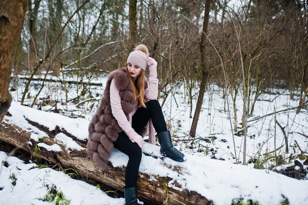 Stilvolle Frau im Pelzmantel und im Headwear am Winterwald.