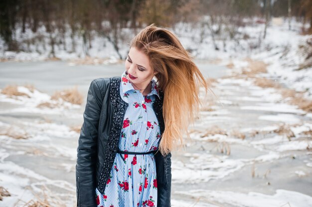 Stilvolle Frau in der Lederjacke am Wintertag gegen gefrorenen See.