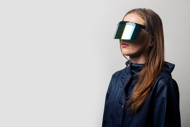 Stilvolle Frau in VR-Brille und in blauer Jacke auf hellem Hintergrund