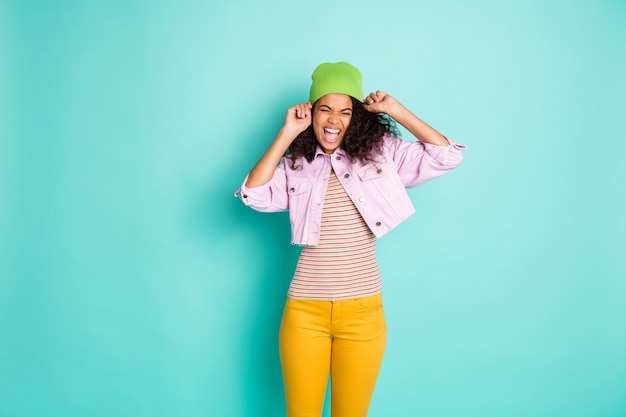 Stilvolle Frau mit Afro-Frisur, die gegen die blaue Wand aufwirft