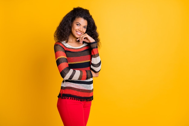 Stilvolle Frau mit Afro-Frisur, die gegen die orange Wand aufwirft