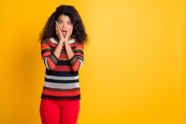 Stilvolle Frau mit Afro-Frisur, die gegen die orange Wand aufwirft