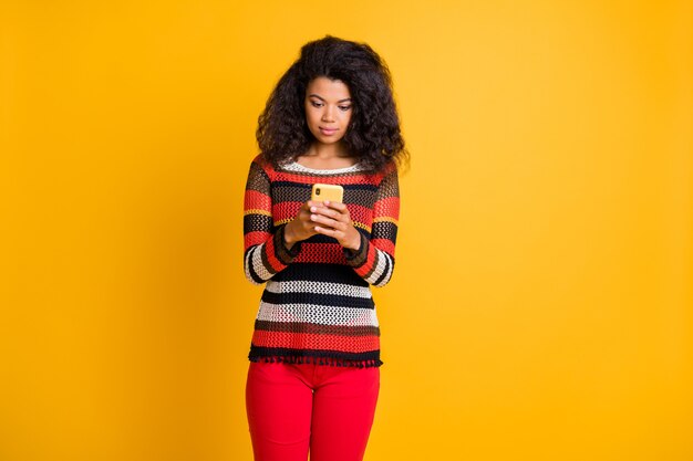 Stilvolle Frau mit Afro-Frisur, die gegen die orange Wand aufwirft