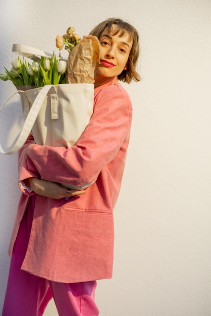 Stilvolle Frau mit Tragetasche und Blumen im Hintergrund