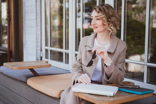 Stilvolle Geschäftsfrau in einem Straßencafé, die am Laptop arbeitet